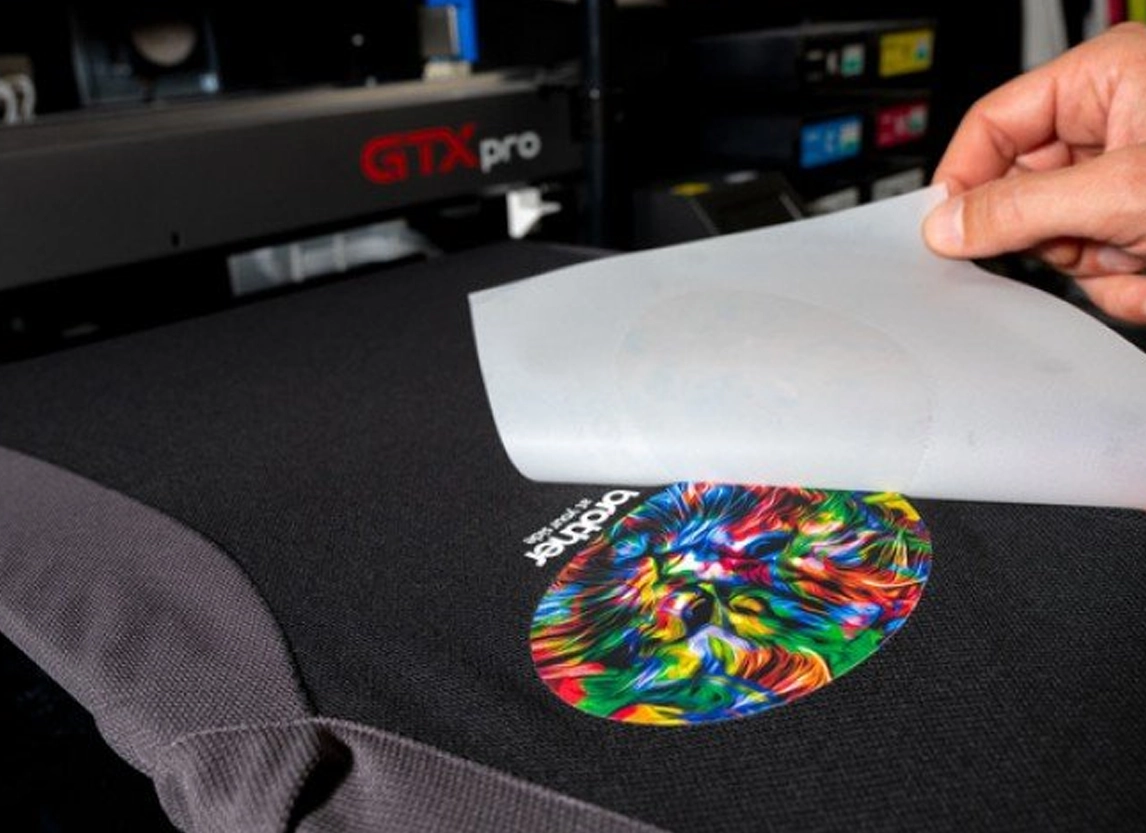 dtf transfer sheet being applied to black t-shirt with colorful custom design